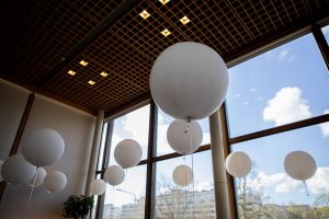 På bilden finns ett tiotal vita jätteballonger som svävar mot taket i en Åbo stadsteaters foajé.