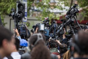 På bilden trängs journalister som håller kameror och mikrofoner över sina huvuden.