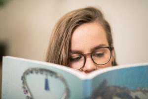 En studerande läser en bok. Boken täcker nästan ansikter, man ser endast hens ögon.