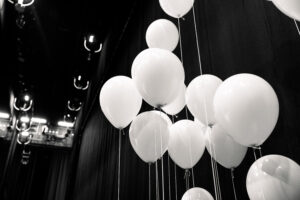 Ett svartvitt fotografi föreställandes vita ballonger med snören.